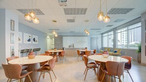 Una sala de conferencias moderna con mesas redondas, sillas cómodas e iluminación colgante.
