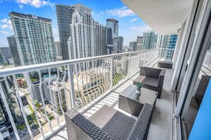 A balcony with wicker furniture and a view of high-rise buildings. - Amazing spacious unit (Miami)