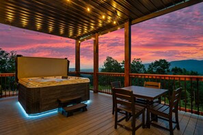 Un bain à remous sur une terrasse en bois, avec une table et des chaises, offrant une vue panoramique.