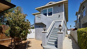 Une maison moderne à deux étages, dotée d’un escalier au design original, d’un numéro de maison bien visible et d’un jardin bien entretenu.