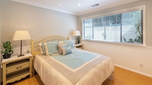 A bedroom with a bed, two bedside tables with lamps, a potted plant, and a window with blinds. - Secluded Private Suite in Bridle Trails – Near Major Tech & 25 Min to Seattle (Bellevue)