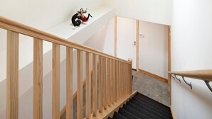 A wooden staircase with a handrail, a small shelf with a decorative item, and a door at the bottom. - Avonside Alpine Estate - Jindabyne (Avonside)