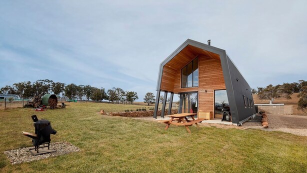 A modern, two-story cabin with a sloped roof, large windows, and a wooden deck. - Avonside Alpine Estate - Jindabyne (Avonside)