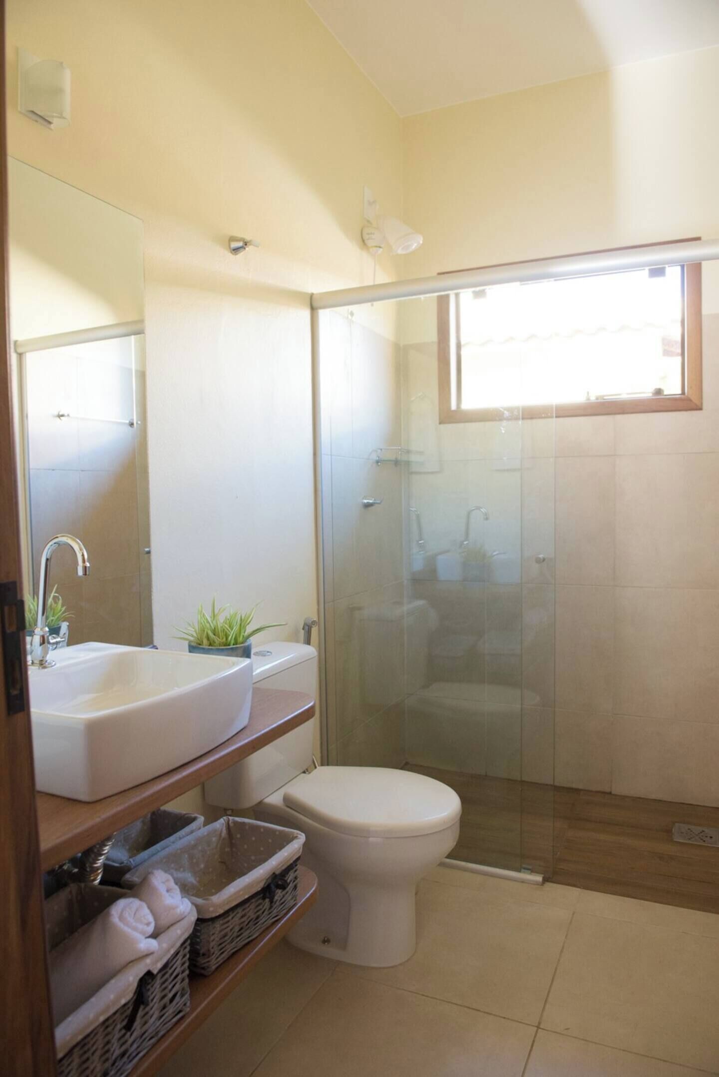 A bathroom with a glass-enclosed shower, a sink with a mirror, and a toilet.