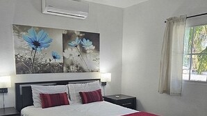 Un dormitorio moderno con una cama, mesitas de noche, un ventilador de techo y obras de arte en la pared.