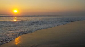 Una playa con el sol poniéndose sobre el océano, creando una atmósfera tranquila y serena.
