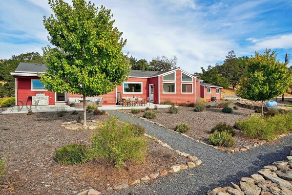 A red two-story house with a patio and a gravel driveway. - Cottage Retreat at Paradise Ridge by Kohmsa (Santa Rosa)