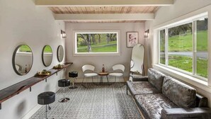 A modern room with a wooden ceiling, a large window with a view of a green landscape, a sofa, two chairs, a small table, and a mirror on the wall. - Cottage Retreat at Paradise Ridge by Kohmsa (Santa Rosa)