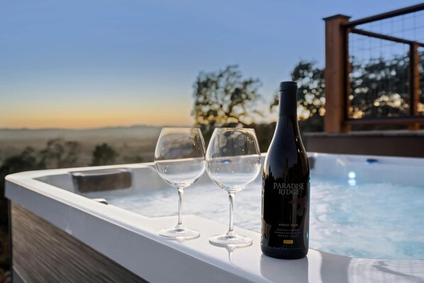 A hot tub with two empty wine glasses and a bottle of Paradise Ridge Pinot Noir wine.