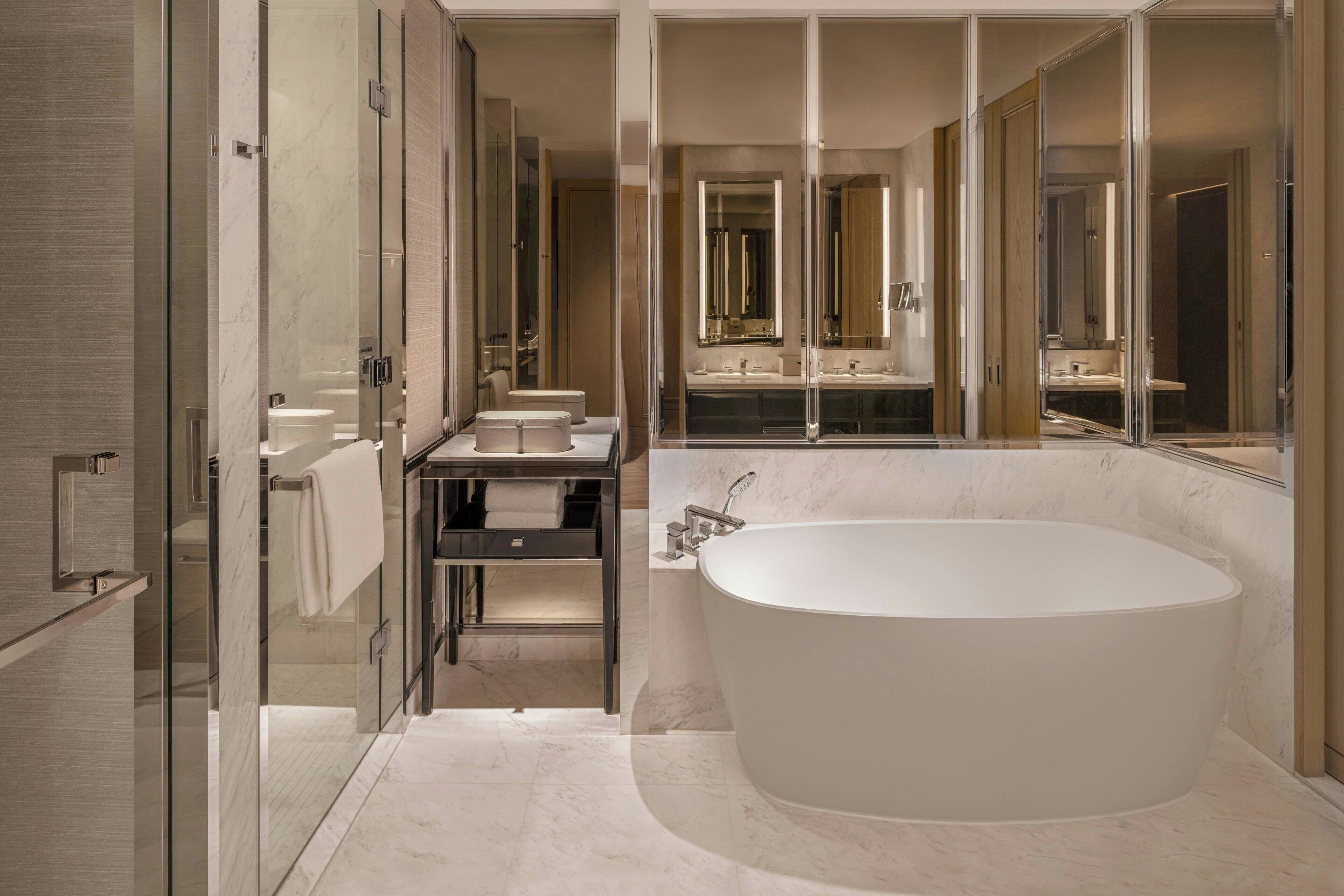 Een moderne badkamer met een vrijstaand bad, een douche met glazen wanden en een wastafelmeubel met spiegel.