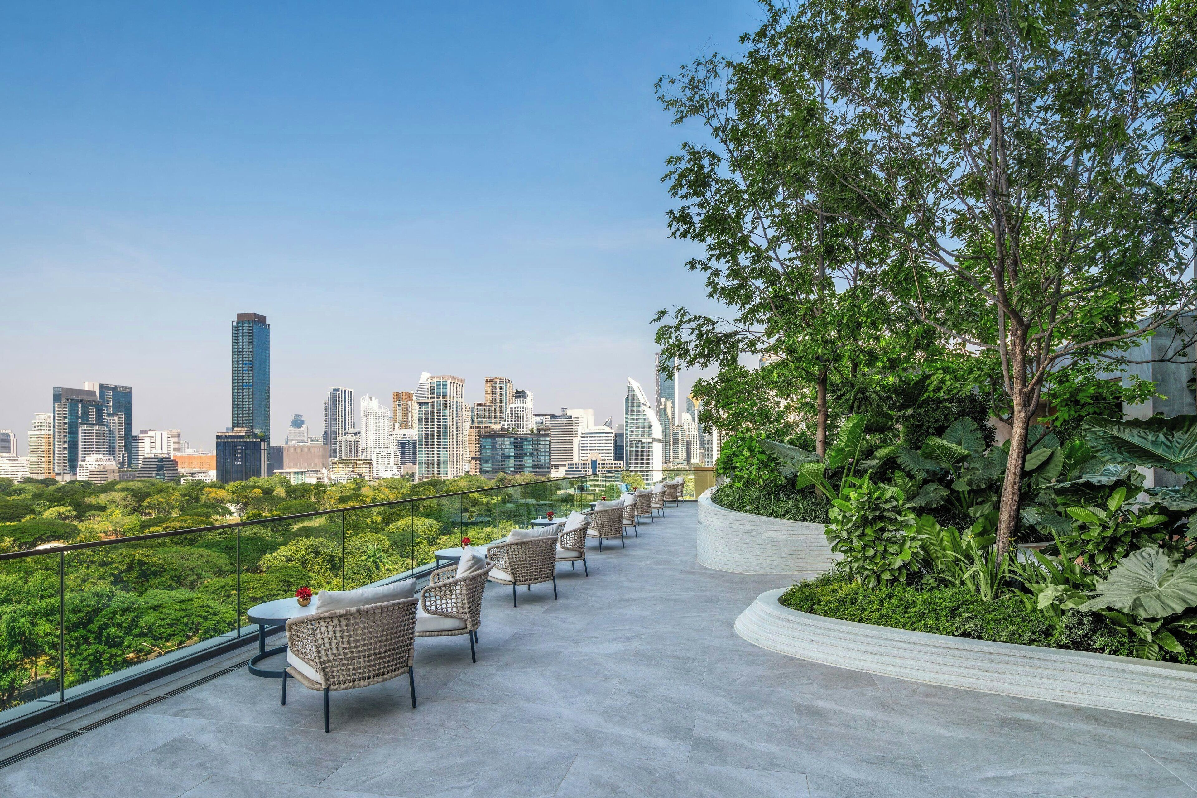 Une terrasse sur le toit avec des sièges extérieurs, une vue panoramique sur la ville et un jardin aménagé.