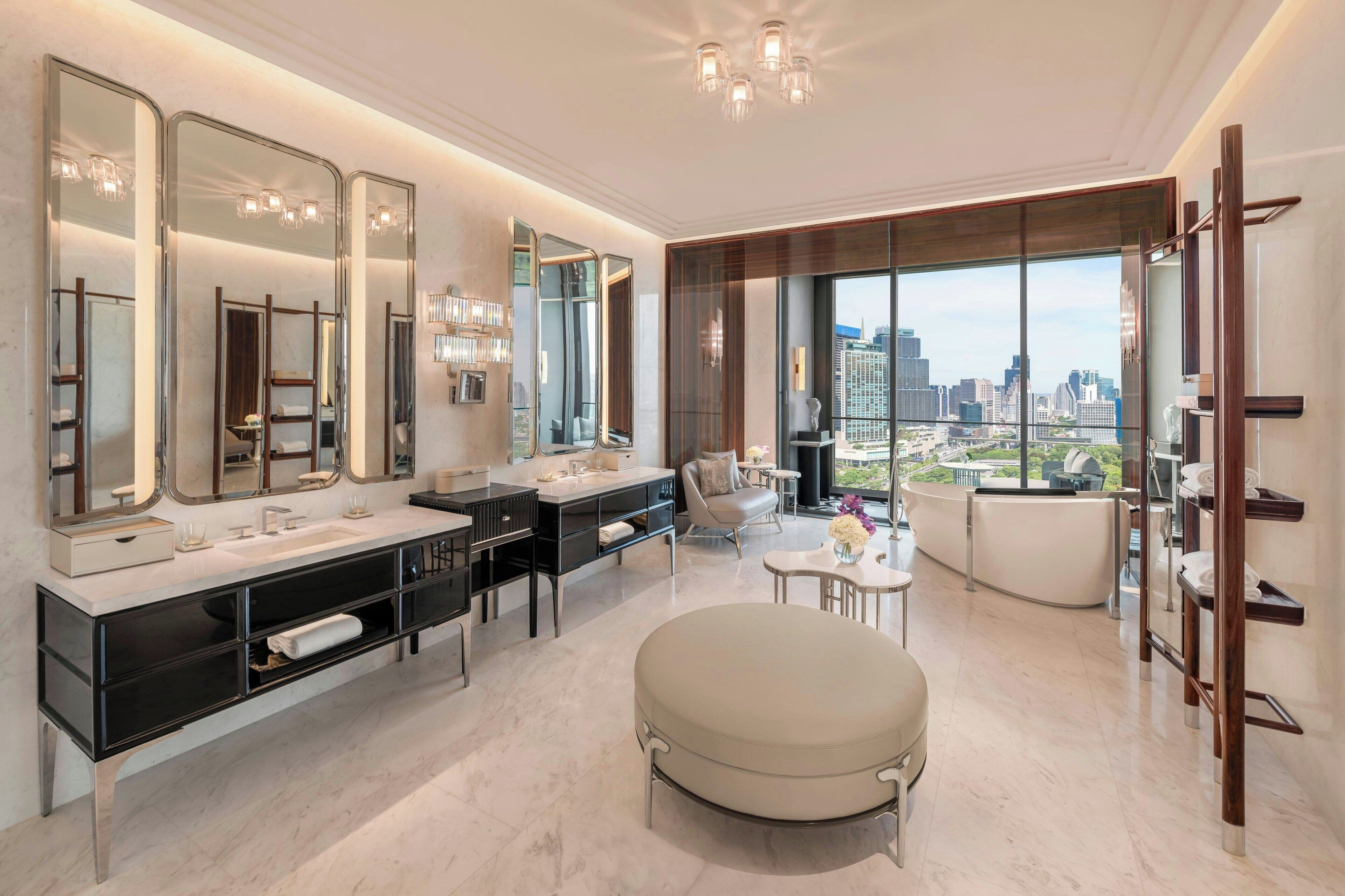 A modern bathroom with dual sinks, large mirrors, and a city view.