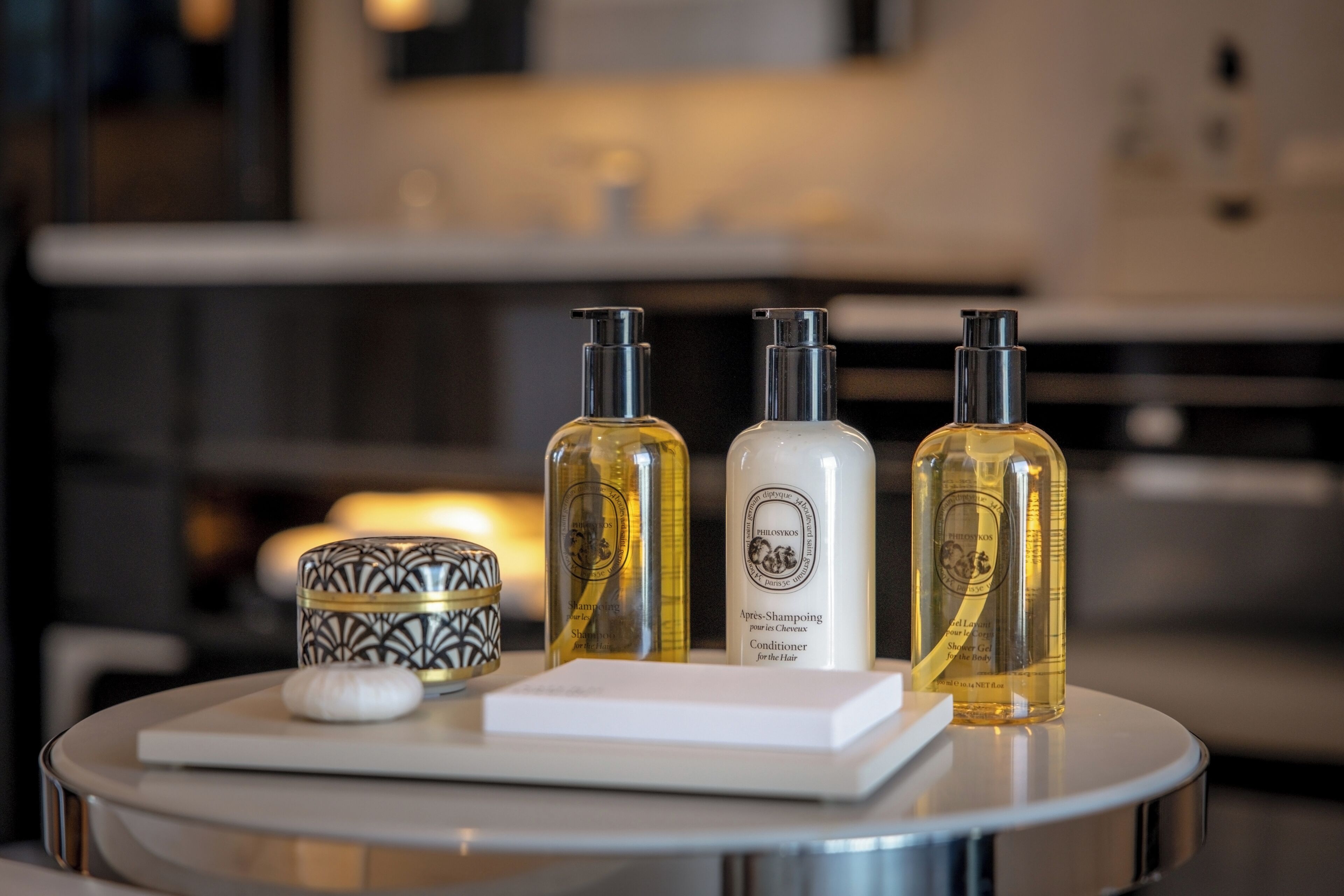 A bathroom vanity with three bottles of shampoo and conditioner, a soap bar, and a decorative container.
