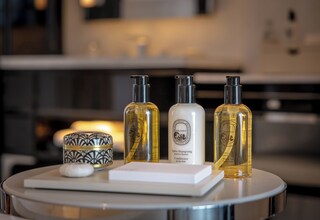 A bathroom vanity with three bottles of shampoo and conditioner, a soap bar, and a decorative container.
