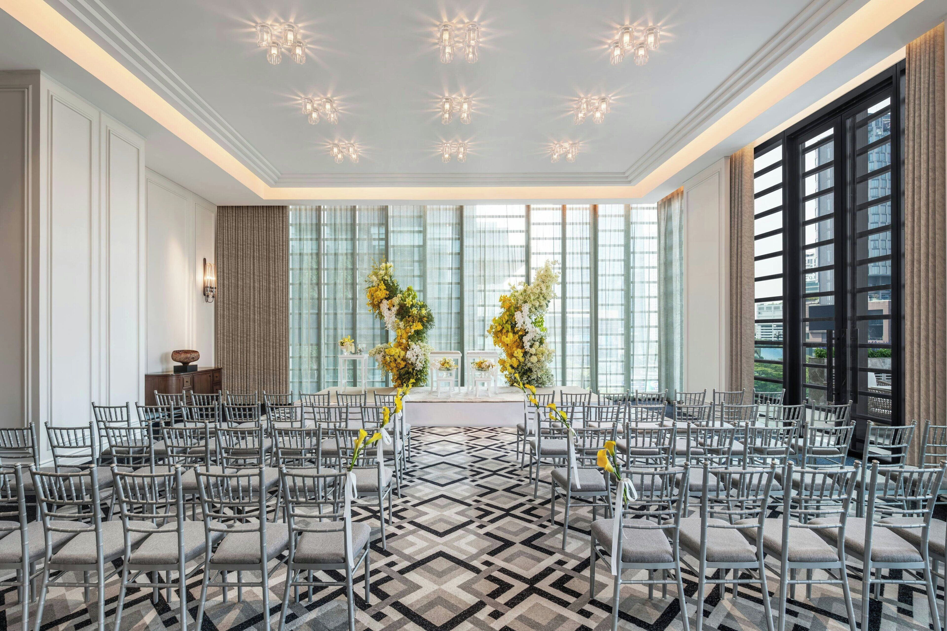 A conference room with a geometric patterned floor, rows of grey chairs, and a central aisle.