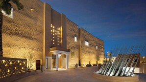 A modern building with a textured facade, a well-lit entrance, and a decorative arrangement of objects in the foreground. - Bab Samhan, A Luxury Collection Hotel, Diriyah (Diryah)