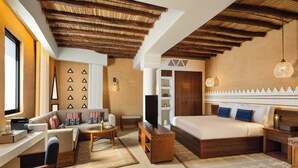 A modern hotel room with a wooden ceiling, a large bed, a sofa, a TV, and a desk with a computer. - Bab Samhan, A Luxury Collection Hotel, Diriyah (Diryah)