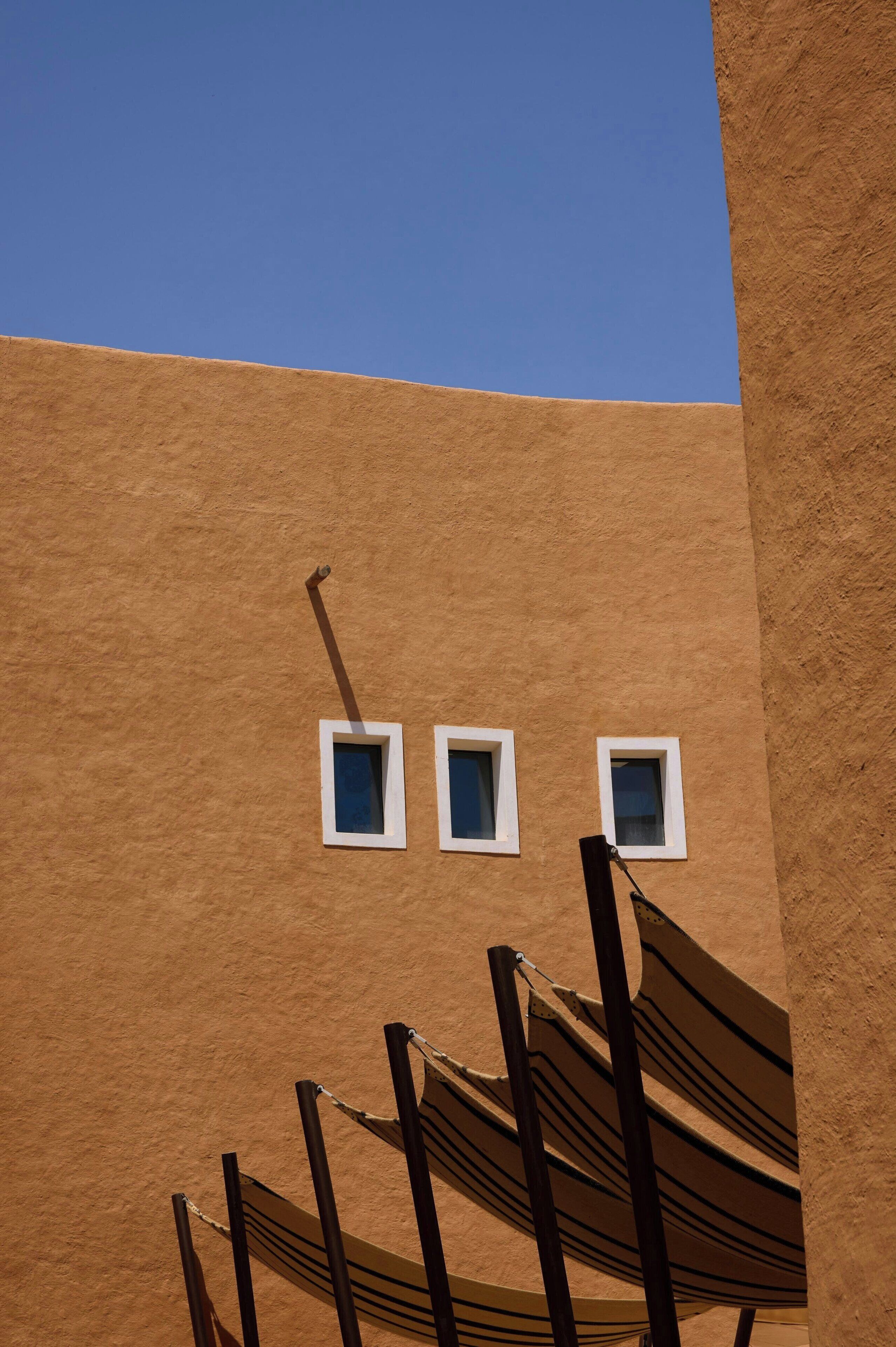 A building facade with three small windows and a hammock.