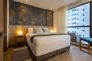 Ein modernes Hotelzimmer mit einem großen Bett, zwei Nachttischen mit Lampen, Blick auf ein Gebäude durch ein großes Fenster und Holzboden.