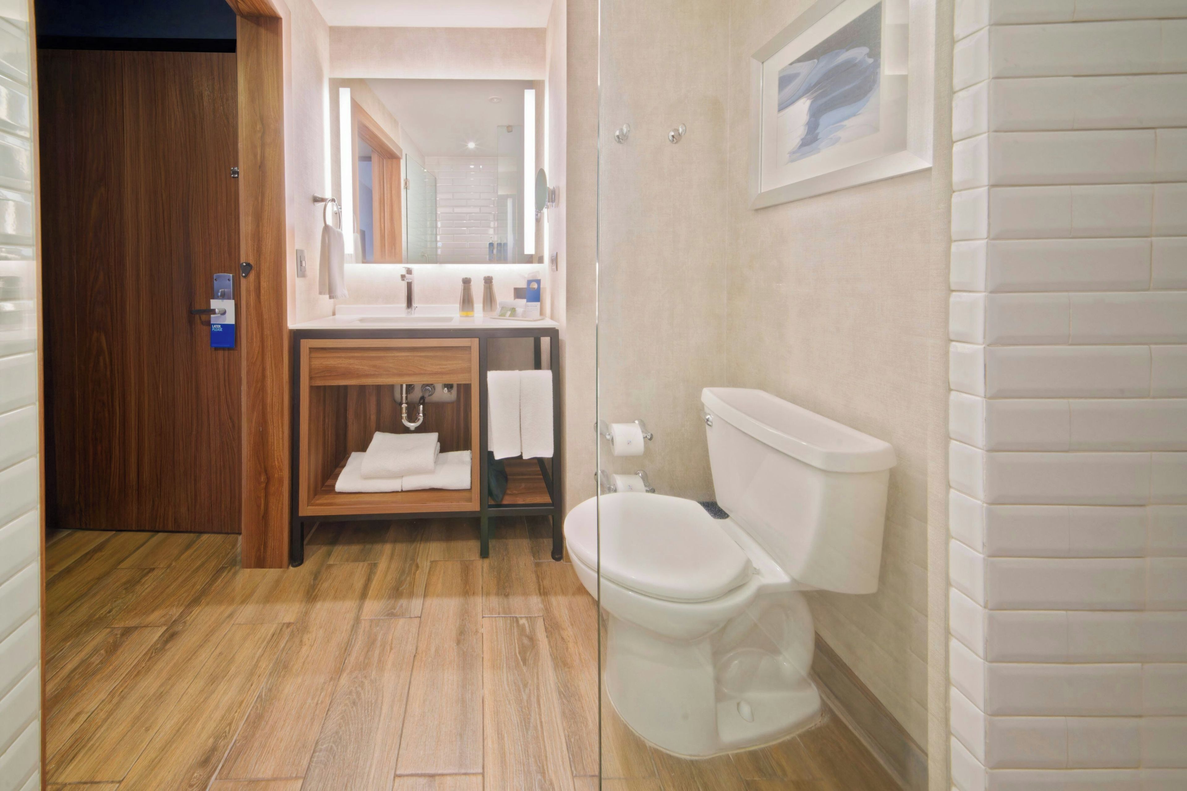 A bathroom with a wooden vanity, a toilet, and a shower area.