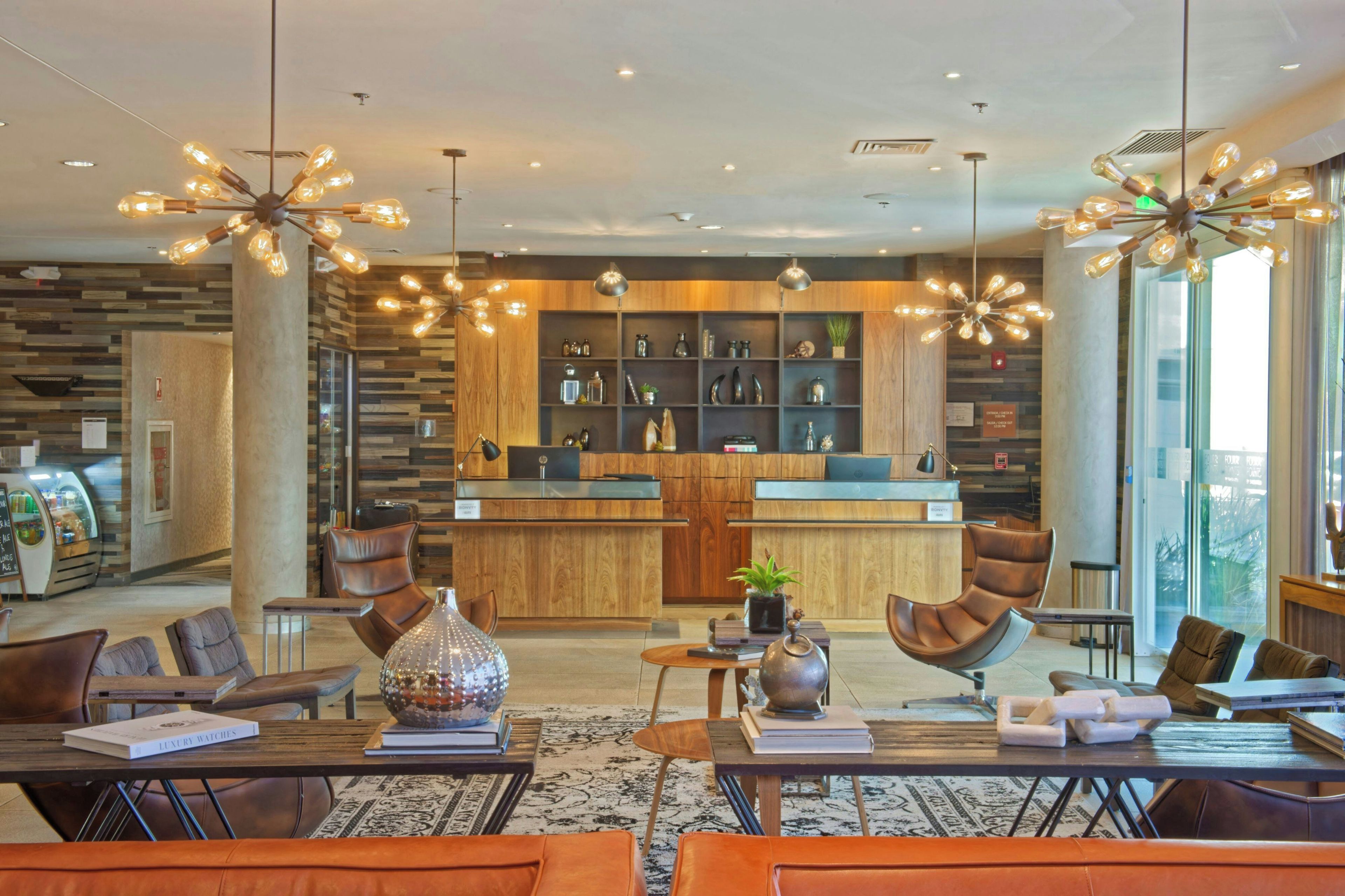 A modern hotel lobby with a central bar area, seating arrangements, and decorative lighting.