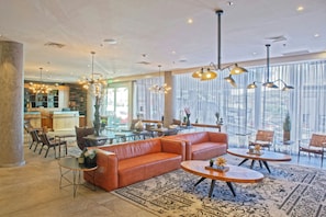 A spacious lobby with a leather sofa, round tables, and a large window with curtains. - Four Points By Sheraton Distrito Uno Chihuahua (Chihuahua)