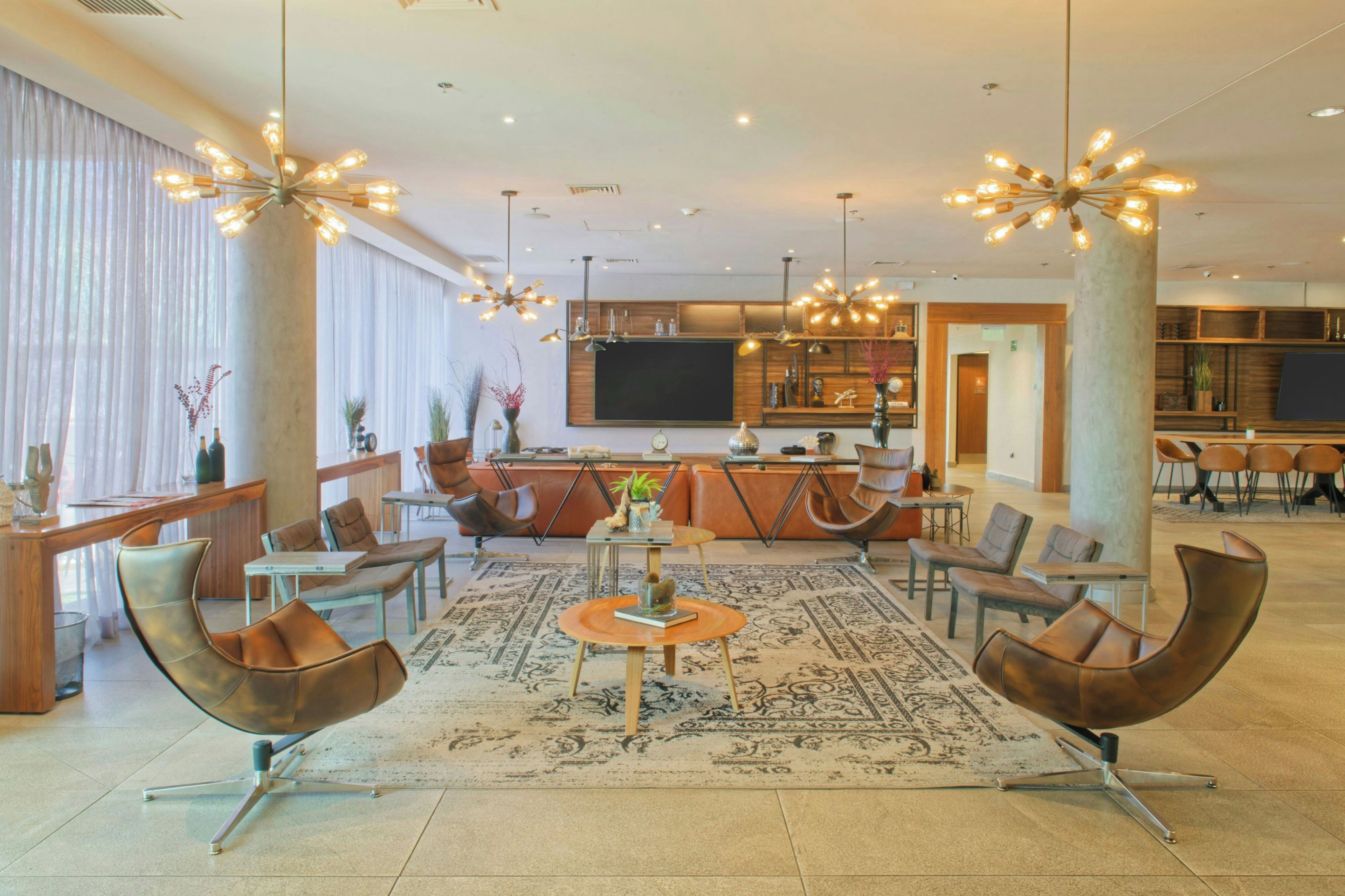 A spacious lobby with leather chairs, a central coffee table, and a large rug.