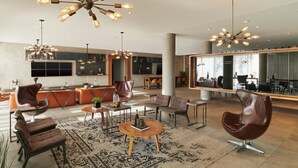 Un vestíbulo amplio con mobiliario moderno, una mesa de centro y varias zonas de estar.