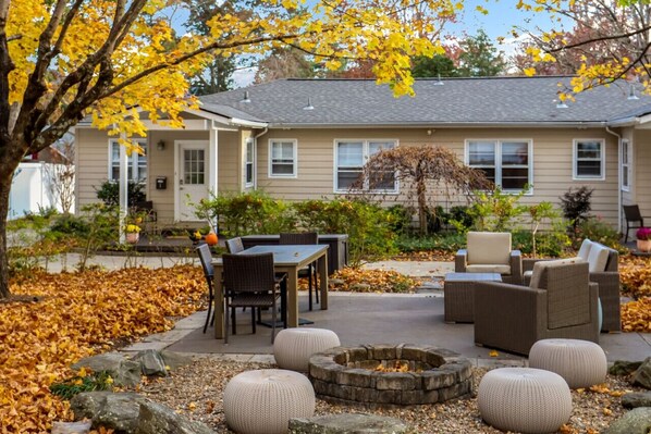 A house with a patio area featuring a table, chairs, and a fire pit.