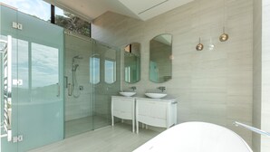 A modern bathroom with a glass-enclosed shower, a freestanding bathtub, and a double vanity with two sinks.