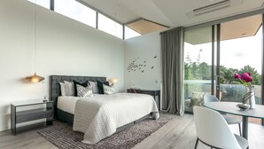 Un dormitorio moderno con una cama grande, una mesita de vidrio y un balcón con vistas.