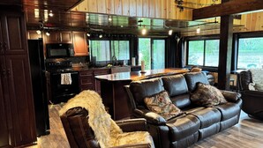 A cozy living room with a leather sofa, a fur throw, and a wooden dining table.