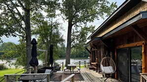 A wooden deck with outdoor furniture, a covered seating area, and a view of a lake.