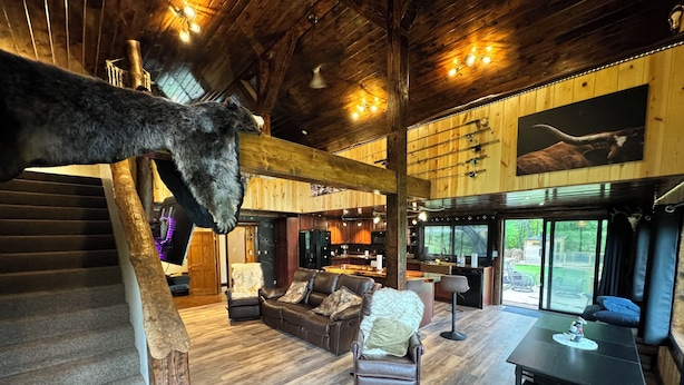 A spacious living area with a staircase, leather furniture, and a mounted animal head.
