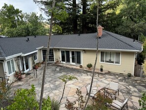 Enjoy a peaceful retreat in this two-story house surrounded by lush greenery and a covered patio with seating area.