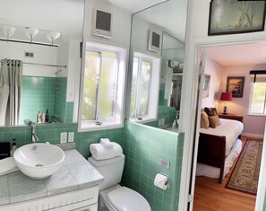 Bathroom features a sink, toilet, and shower area with a mirror above the sink.