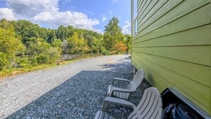 A gravel driveway leading to a green building with a row of white chairs outside. - The Florio, Tiny Home, River, Hiking, and Rafting! (Sylva)