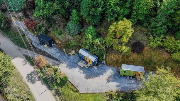 An aerial view of a property with two small buildings, a gravel driveway, and surrounding greenery. - The Florio, Tiny Home, River, Hiking, and Rafting! (Sylva)