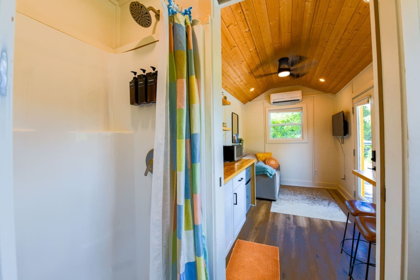Una cocina compacta con suelo de madera, una ventana y una zona de bar.