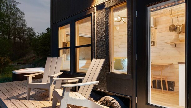 A modern cabin with a deck, two chairs, and a table.