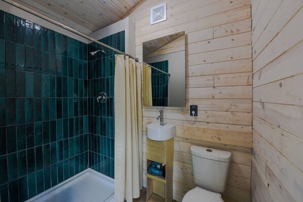 Une salle de bain équipée d’une douche, de toilettes, d’un lavabo et d’un miroir.