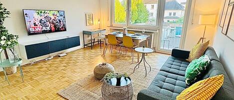 Una sala de estar moderna con un sofá, una mesa de centro y un televisor montado en la pared.