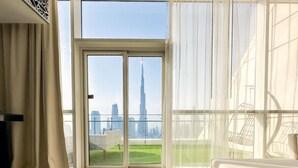 A modern living room with a large glass door leading to a balcony with a city view. - Panoramic Burj Khalifa View Luxury Penthouse 1BR (Dubai)