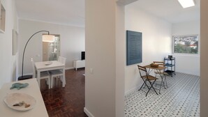 Una sala de estar moderna con comedor, un ventanal con vistas a la ciudad y un suelo estampado.