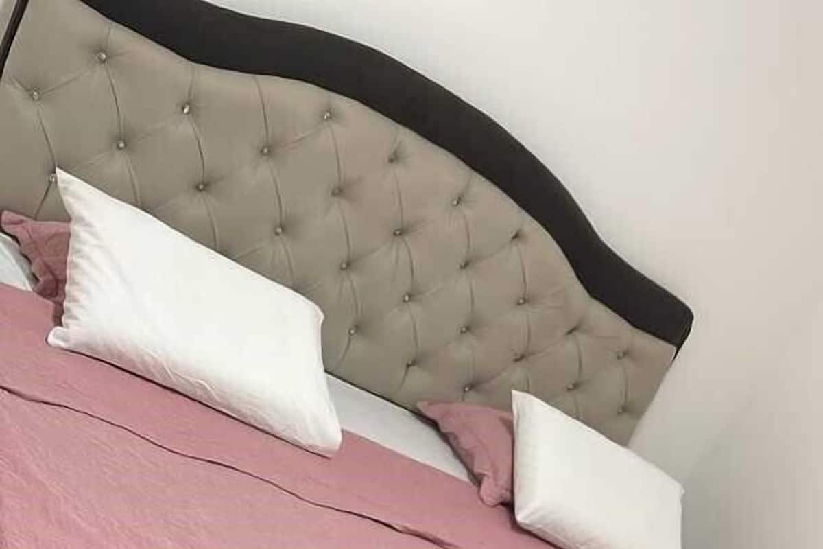A neatly made bed with a tufted headboard, pink bedding, and two white pillows.