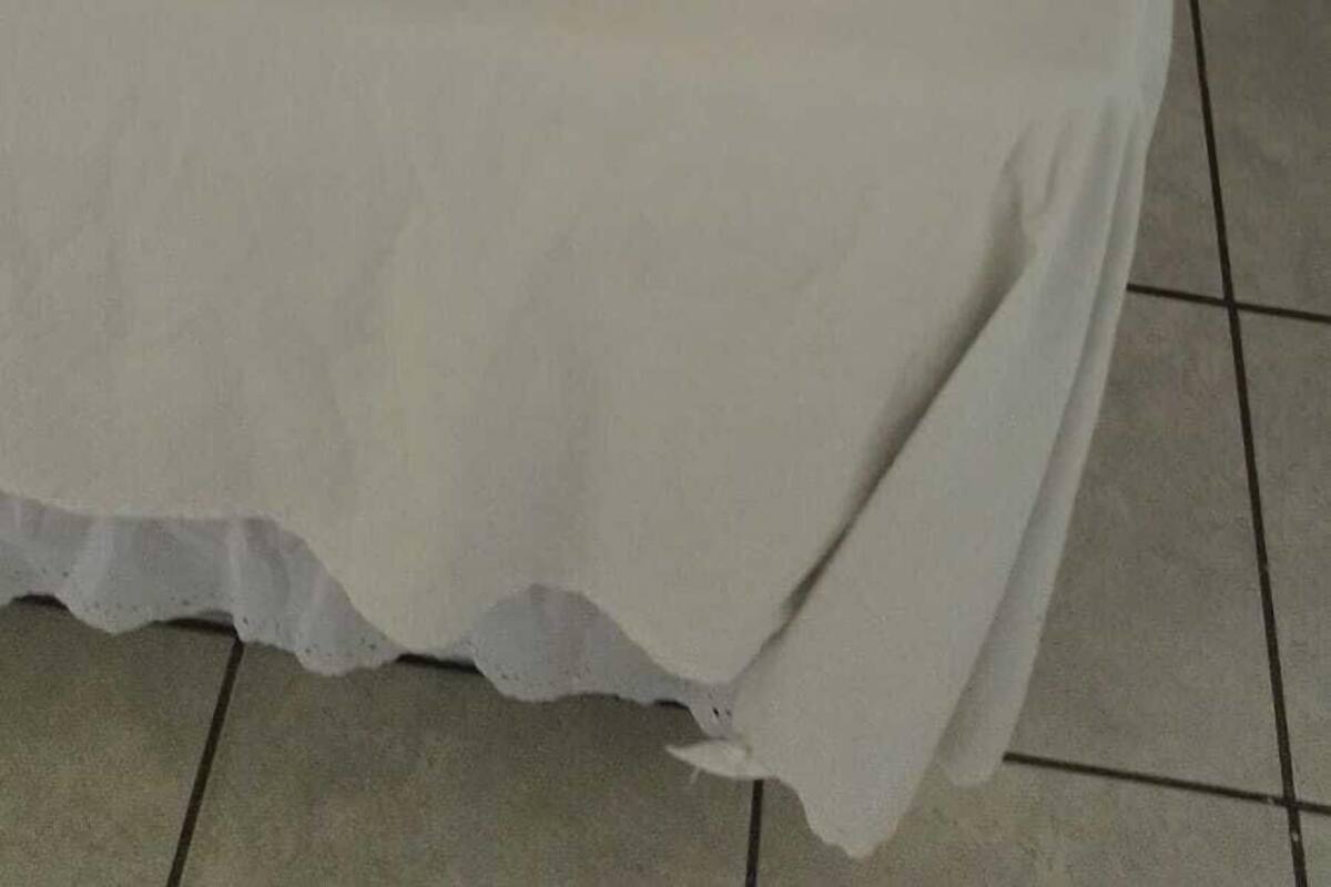 A neatly made bed with a white sheet and a folded white towel placed on the bed.
