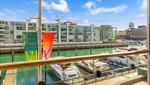 Un port de plaisance avec des bateaux amarrés, une grue de construction et des bâtiments modernes en arrière-plan.