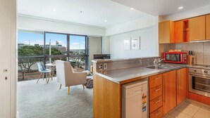 A modern kitchen with wooden cabinets, stainless steel appliances, and a large window offering a city view. - Viaduct Harbour Views w/ Free Parking-Zodiak Stays (Auckland)