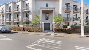 A multi-story residential building with balconies, a gated entrance, and a clear street view. - 1BR Grey Lynn Haven+Parking, Balcony Zodiak Stays (Auckland)
