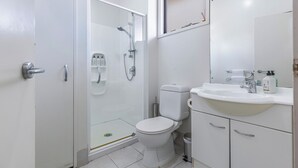 A modern bathroom with a glass-enclosed shower, a white toilet, and a sink with a mirror above it. - 1BR Grey Lynn Haven+Parking, Balcony Zodiak Stays (Auckland)